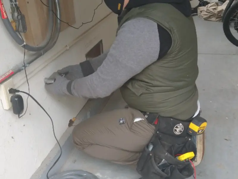 Electrician performing outlet wiring in a Logan garage